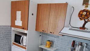 Una cucina compatta con mobili in legno, un forno a microonde, un fornello a gas e un lavandino.