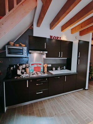 Una cocina moderna con armarios oscuros, microondas integrado, estufa a gas y cafetera.