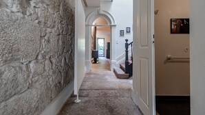 A hallway with a stone wall, a staircase, and a door with a picture on it. - Music Shell by LovelyStay (Porto)