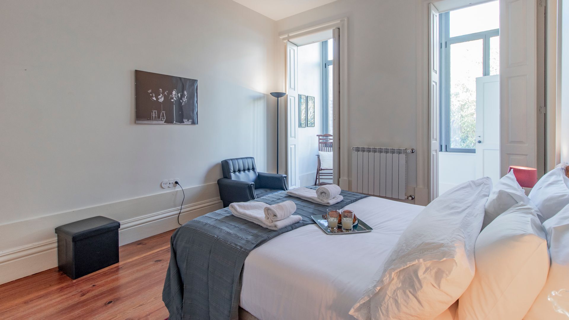 Ein Hotelzimmer mit einem großen Bett, einem Sessel, einem Heizkörper und einem Bild an der Wand.