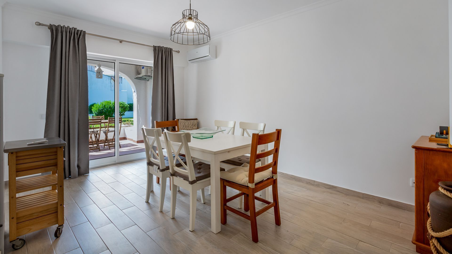 Un comedor con mesa, sillas y vistas a un patio exterior a través de un ventanal.