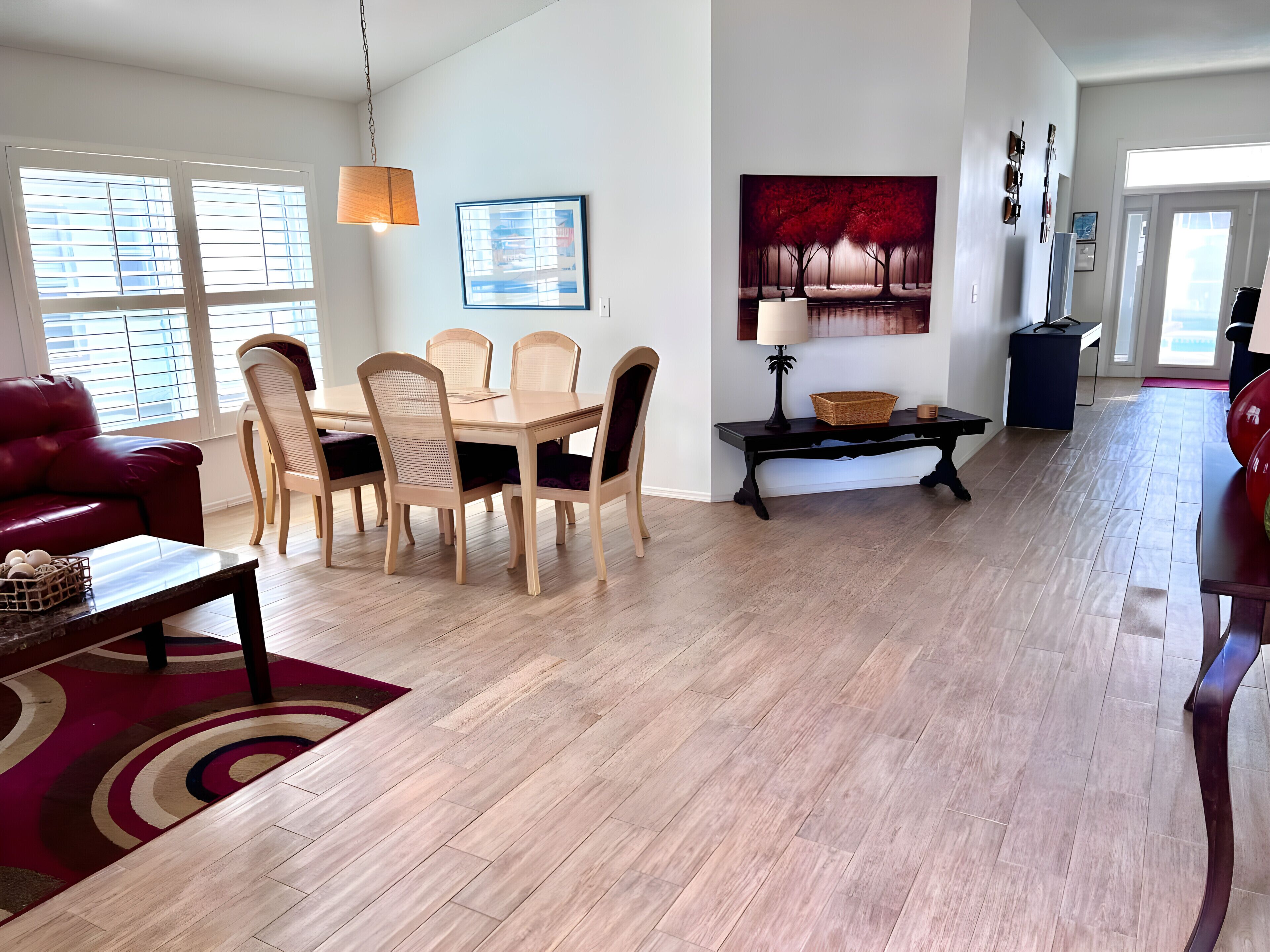 A spacious living area with a dining table, chairs, and a red sofa.