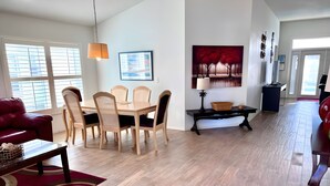 Un amplio salón con una mesa de comedor, sillas y un sofá rojo.