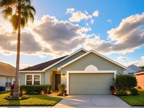 A single-story house with a garage, a well-maintained lawn, and a palm tree. - Villa Brittany | Private Pool • Close to Disney (Kissimmee)