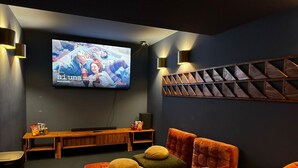 Un cine acogedor con una pantalla grande, asientos cómodos e iluminación instalada en la pared.