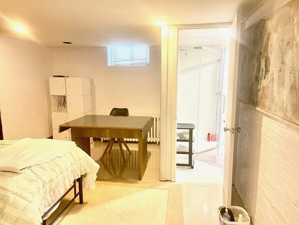 A small, compact room with a bed, a table, and a shower area.
