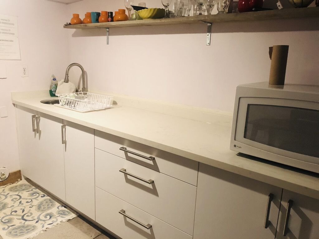 A kitchen with a microwave, a sink, and a basket.