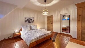 A bedroom with a wooden bed, a ceiling light, a wall tapestry, and a mirror. - Beautiful, spacious holiday apartment in Neroth (Neroth)