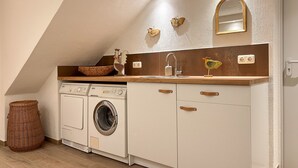 A compact kitchen with a washing machine, a sink, and a mirror. - Beautiful, spacious holiday apartment in Neroth (Neroth)