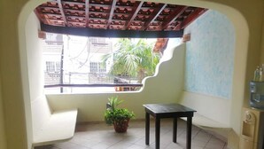 A small, tiled room with a window, a potted plant, a table, and a water dispenser.