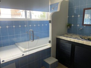 Une salle de bain avec une baignoire, une fenêtre et un lavabo avec un miroir.