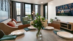Un comedor moderno con una mesa preparada para cuatro personas, un sofá y un gran ventanal con cortinas.