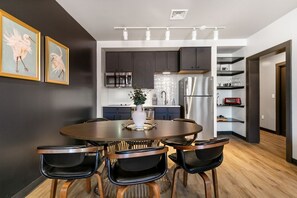A modern kitchen with dark cabinets, stainless steel appliances, and a dining area with a round table and black chairs.