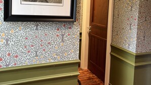 A hallway with patterned wallpaper, a framed artwork, and a wooden door. - Dundrum Inn (Newcastle)