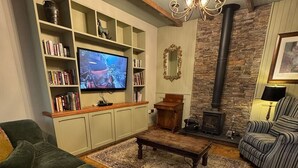 A cozy living room with a television, bookshelves, a fireplace, and comfortable seating. - Dundrum Inn (Newcastle)