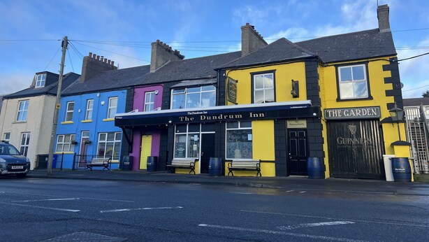A row of colorful buildings with The Dundrum Inn and The Garden pub signs.