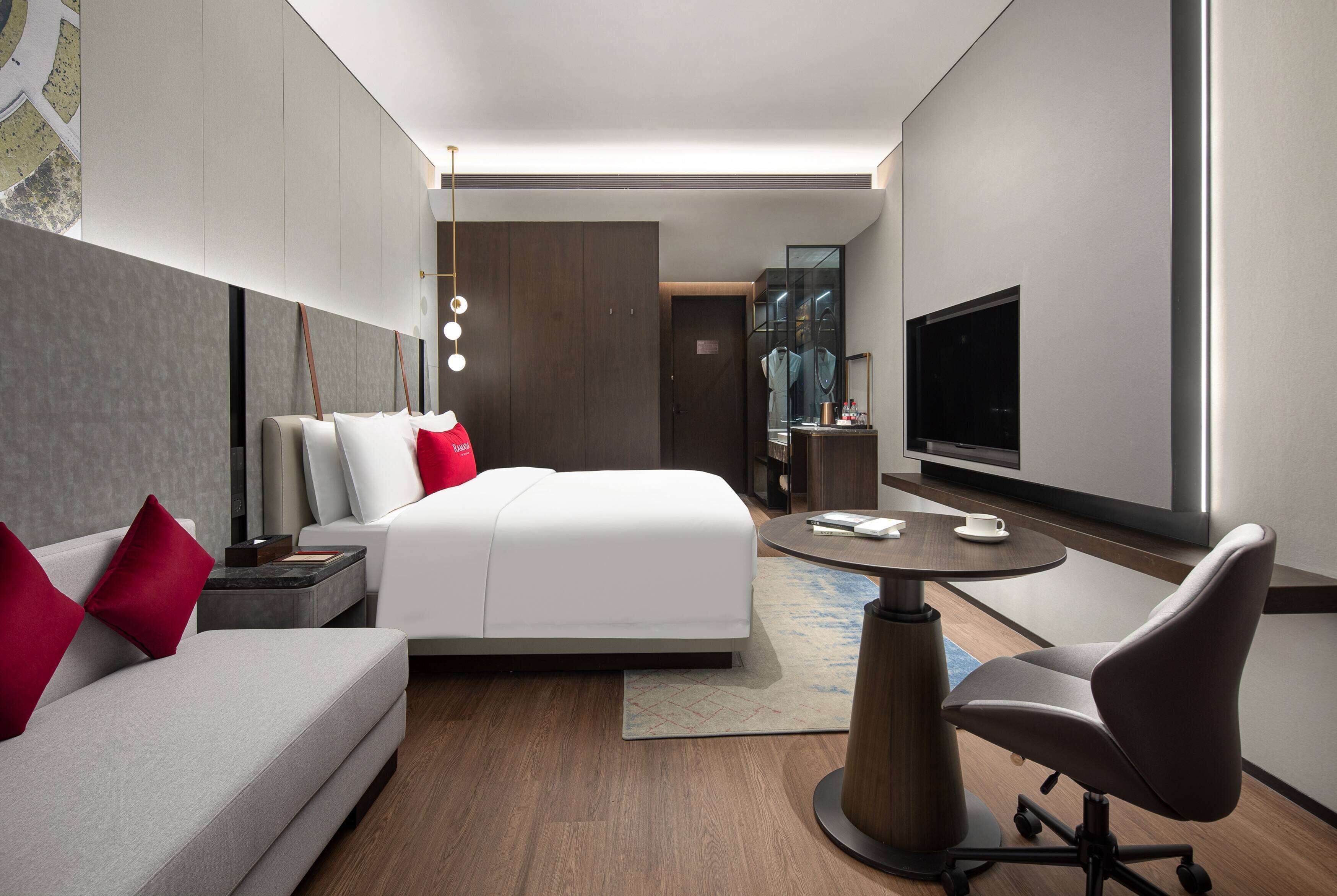 Una habitación de hotel moderna con una cama, un sofá, un escritorio y un televisor.