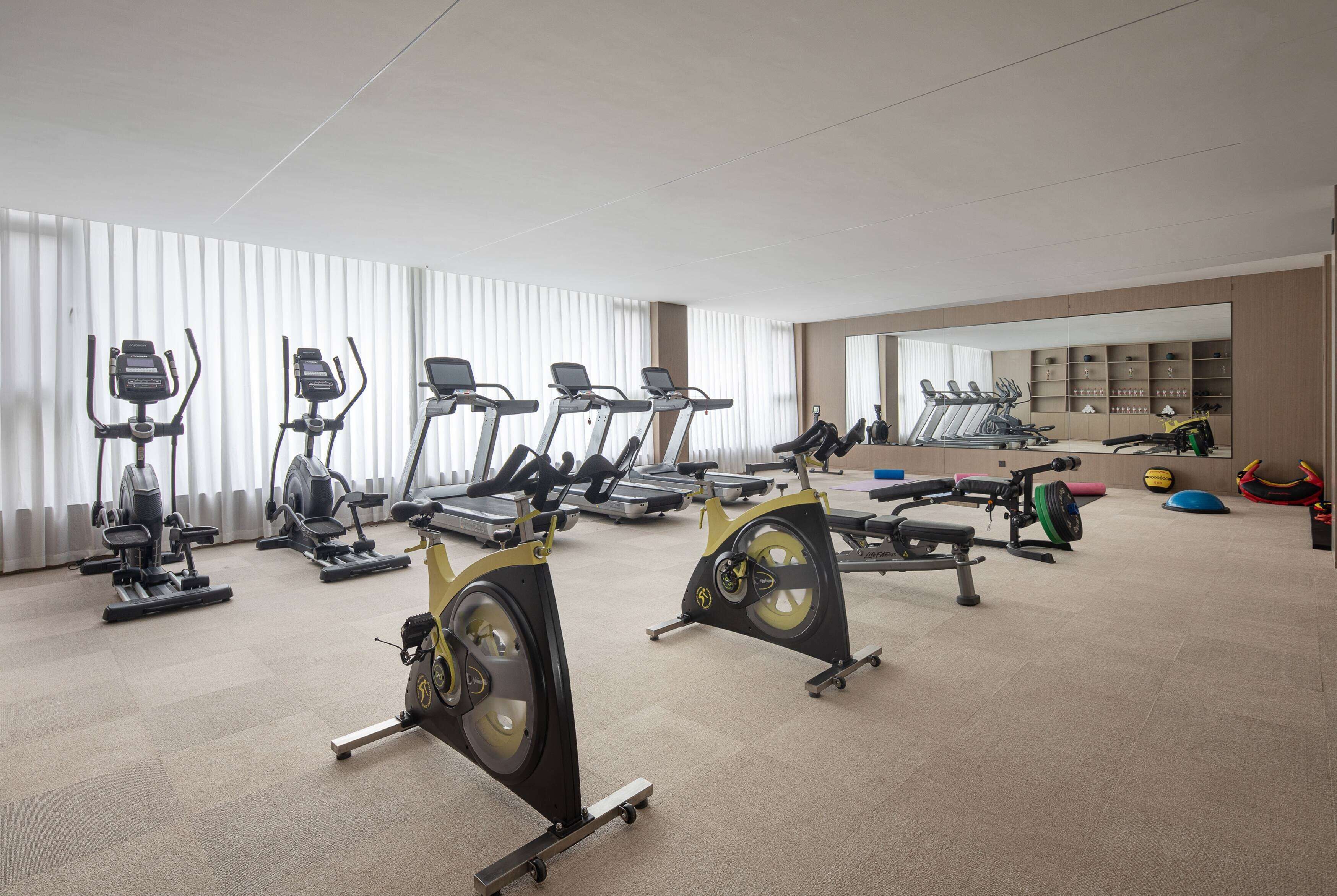 Un gimnasio con bicicletas estáticas, cintas de correr y equipo de pesas.