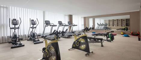 Un gimnasio con bicicletas estáticas, cintas de correr y equipo de pesas.