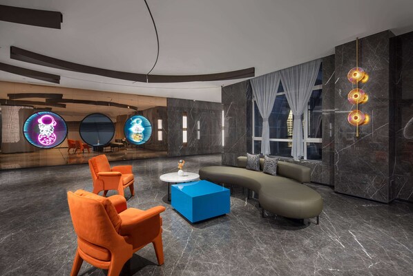 A modern lobby with a blue sofa, orange chairs, and a blue coffee table.
