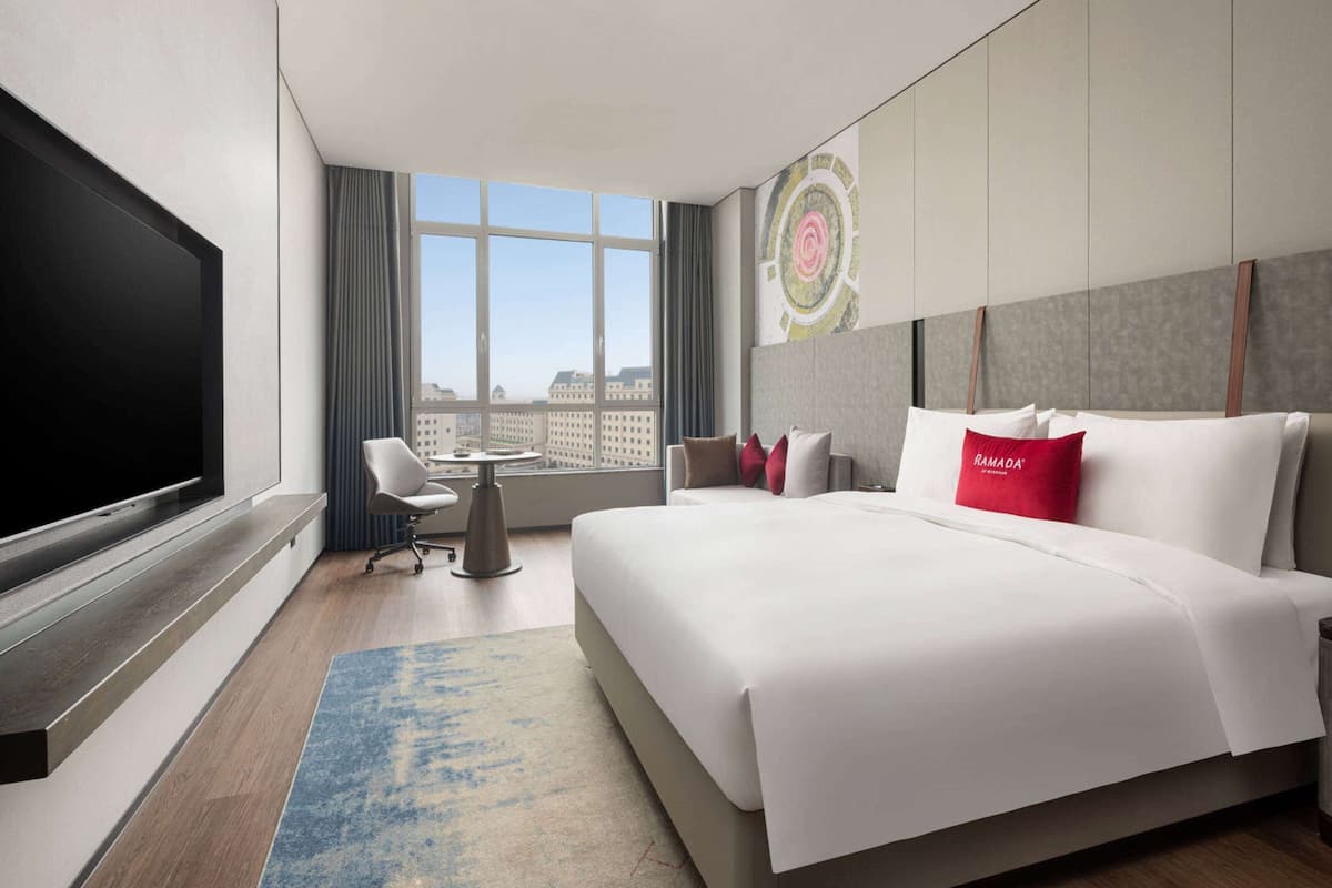 Une chambre d’hôtel moderne dotée d’un grand lit, d’une télévision à écran plat, d’un bureau et offrant une vue sur la ville.