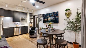 A modern kitchen with dark cabinets, stainless steel appliances, and a dining area with a round table and bar stools.
