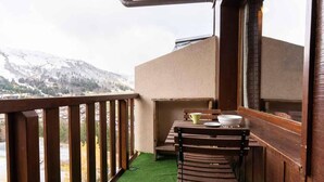 A balcony with a wooden railing, a table with chairs, and a view of snow-covered mountains. - 10th floor, view valley, ski locker, 36m², Valmorel (Valmorel)