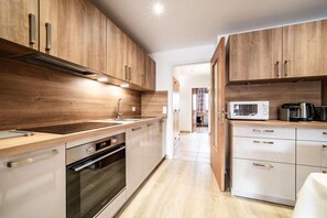 A modern kitchen with wooden cabinets, stainless steel appliances, and a tiled backsplash.