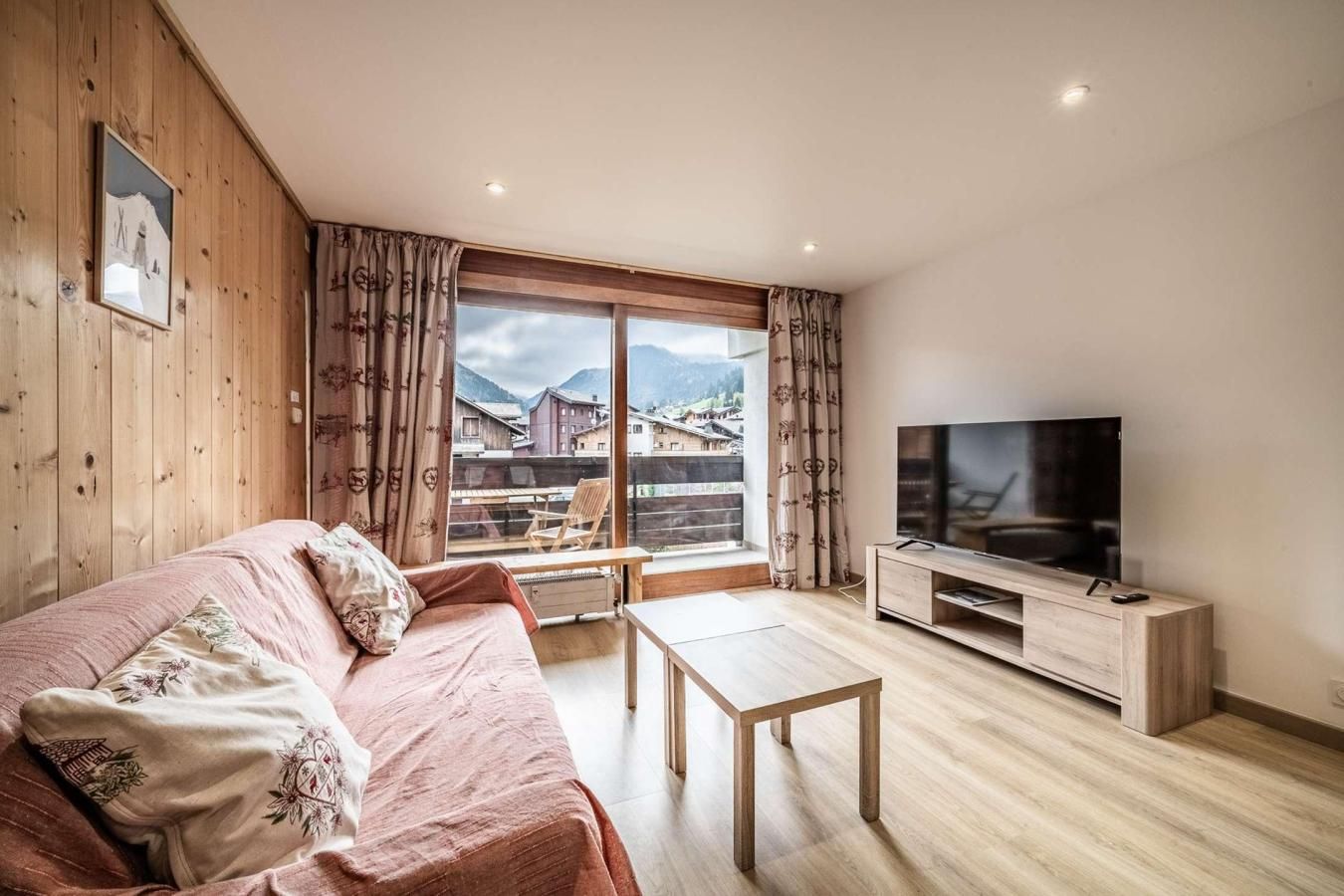 Un salon chaleureux avec un plancher en bois, un canapé, une table basse et un téléviseur.