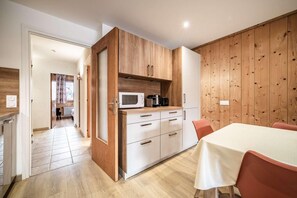 Une cuisine moderne avec des meubles en bois, un four à micro-ondes et une machine à café. Il y a également un coin repas avec une table et des chaises.
