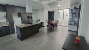 Une cuisine moderne avec des meubles de couleur sombre, un îlot central et un coin repas comprenant des chaises et une table.
