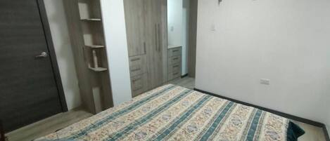 A bedroom with a bed, a wardrobe, and a built-in shelving unit.