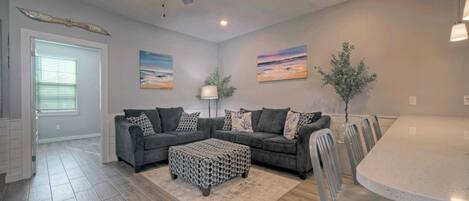 A modern living room with a sectional sofa, a coffee table, and a dining area with a table and chairs.
