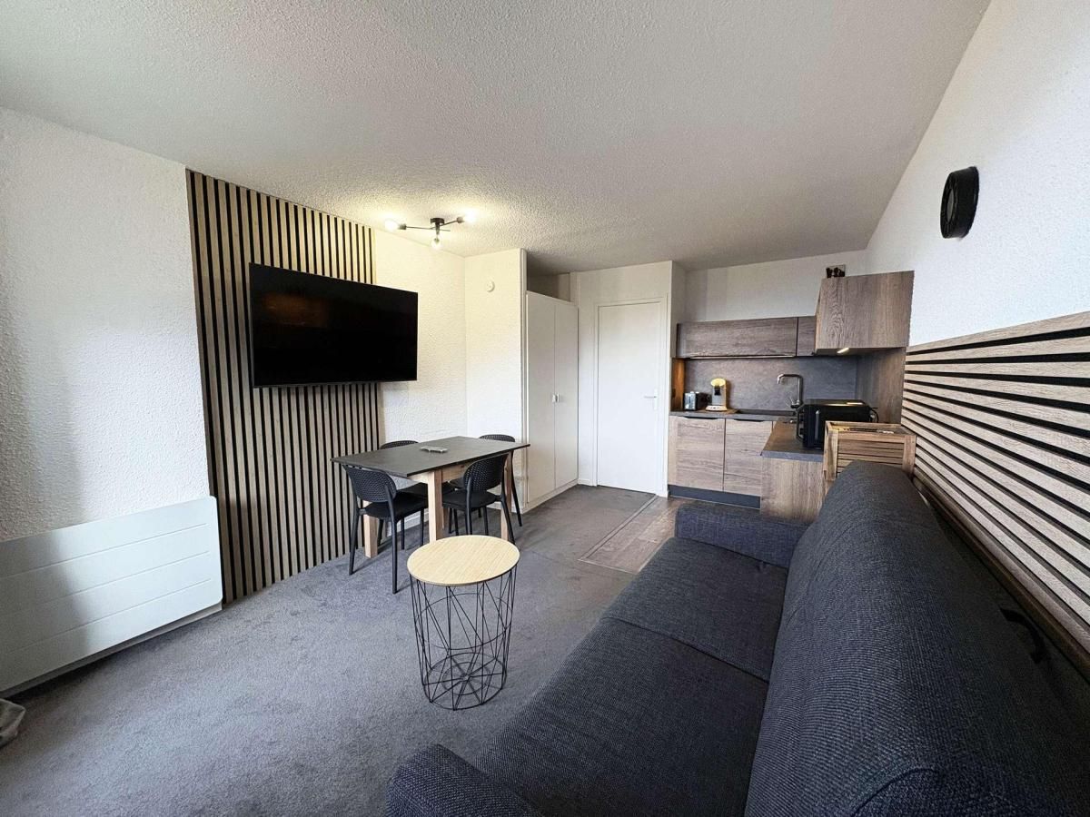 Een knus woongedeelte met een eethoek, kitchenette en een flatscreen televisie aan de wand.