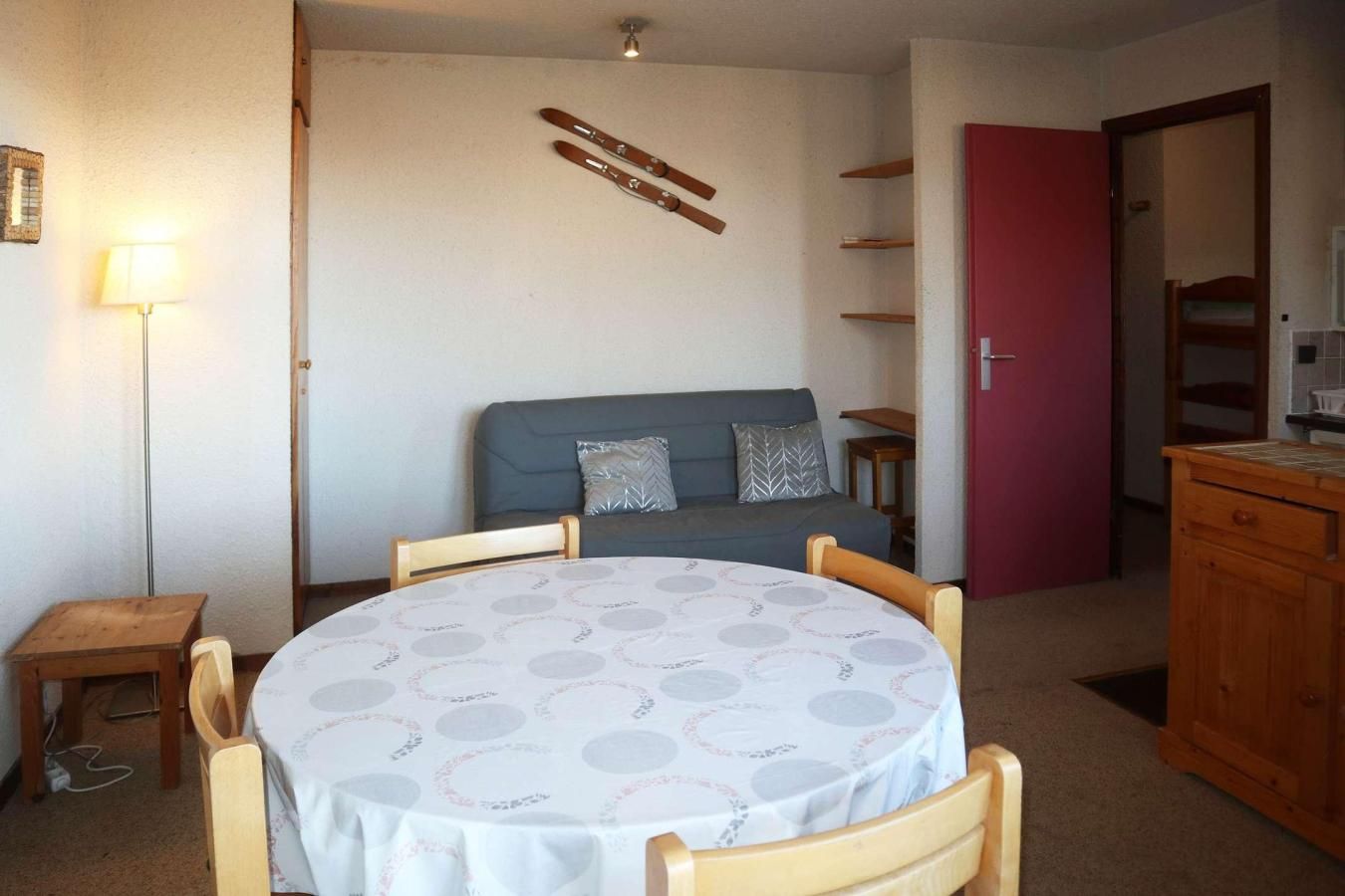 A room with a round table, a sofa, a lamp, and a cabinet.