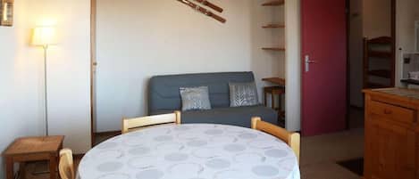 A room with a round table, a sofa, a lamp, and a cabinet.