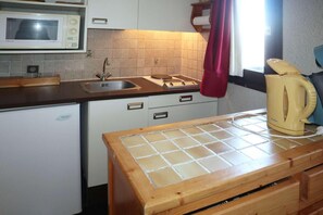 A compact kitchen with a microwave, sink, and a kettle on the counter.