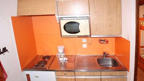 Une cuisine compacte équipée d’un four à micro-ondes, d’une cuisinière, d’un évier et d’un réfrigérateur.