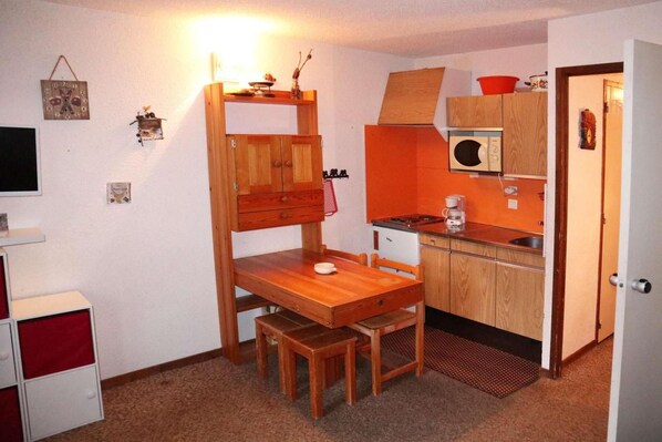 A compact kitchen with a wooden table and bench, a microwave, and a small sink.