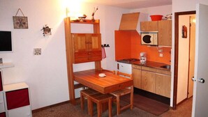 Une cuisine compacte avec une table et un banc en bois, un four à micro-ondes et un petit évier.