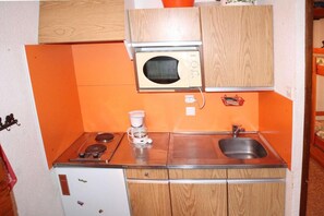 A compact kitchen with a microwave, stove, sink, and refrigerator.