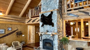 A rustic interior with a stone fireplace, wooden beams, and a cozy seating area. - Ultimate Lakeside Retreat on Flathead Lake near Glacier National Park (Big Arm)