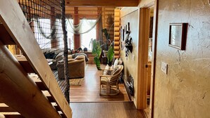 A wooden interior with a staircase, a sofa, a dining table, and a large plant. - Ultimate Lakeside Retreat on Flathead Lake near Glacier National Park (Big Arm)