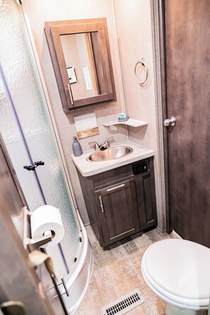 Ein Badezimmer mit Toilette, Waschbecken, Spiegel und Dusche.