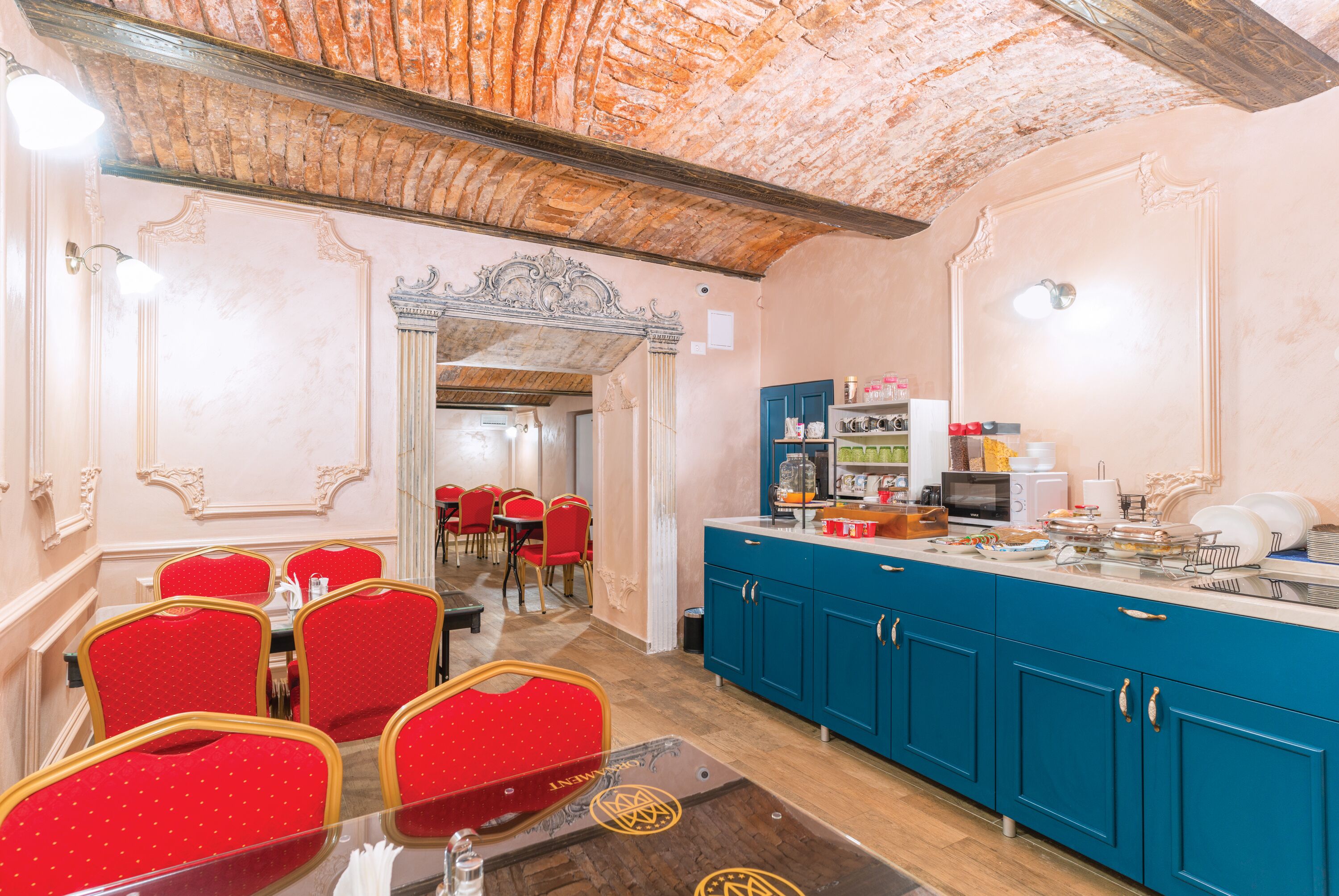 Un espace repas avec des chaises rouges, un comptoir bleu et un plafond en briques.