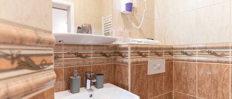 Ein Badezimmer mit Waschbecken, Spiegel, Handtuchhalter und einem an der Wand montierten Föhn.