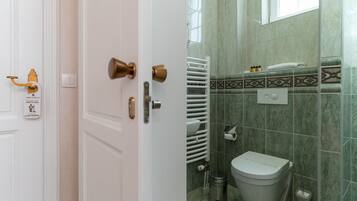 A bathroom with a toilet, a towel rack, and a radiator.