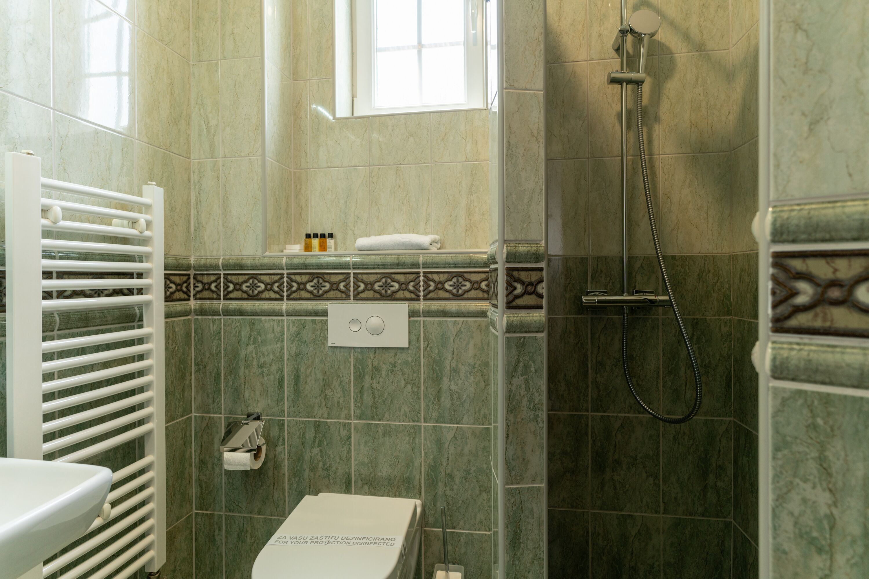 Un baño con ducha, inodoro y toallero.
