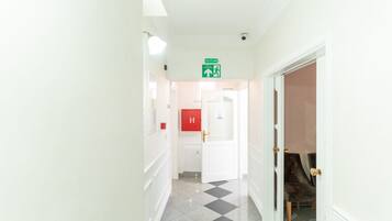 A hotel hallway with a check-in desk, a fire alarm, and a door leading to a room.