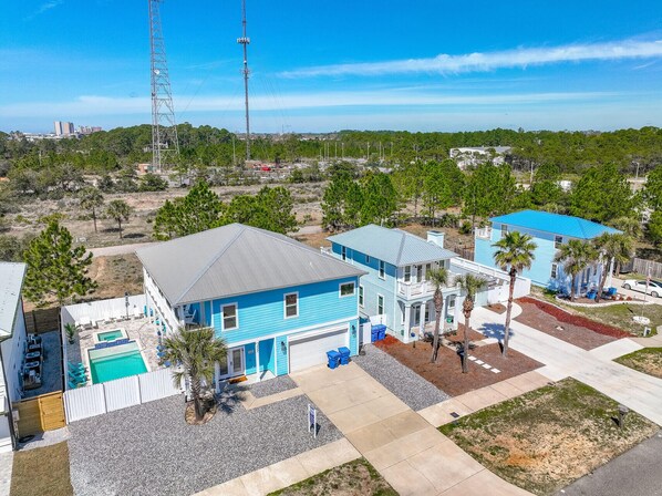 A residential area with houses, a swimming pool, and a large communication tower in the background.